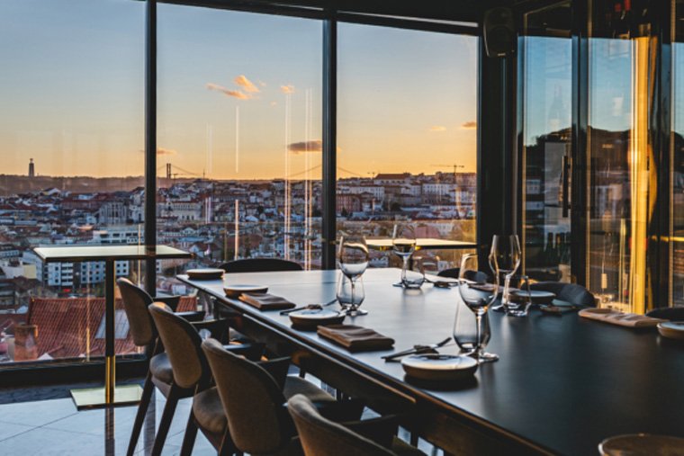 interior do restaurante, com vista para a cidade de Lisboa ao entardecer.