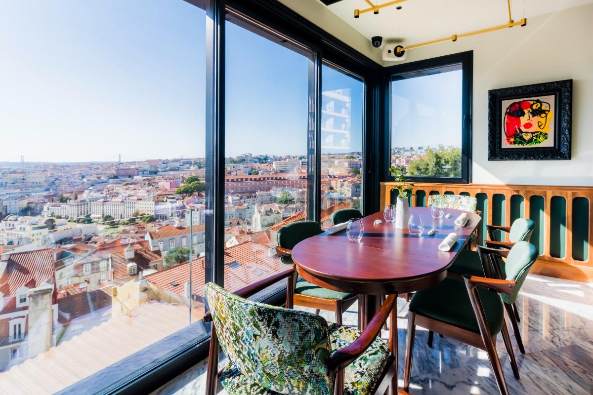 sala de refeições com vista para a cidade de Lisboa. Quadro colorido pendurado na parede.