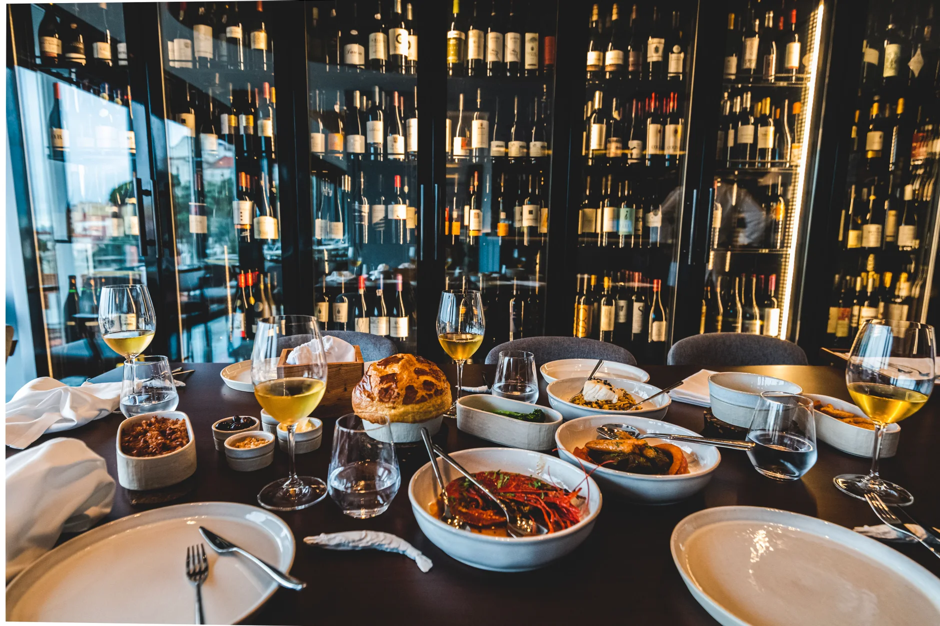 Mesa de restaurante com vários pratos e copos de vinho